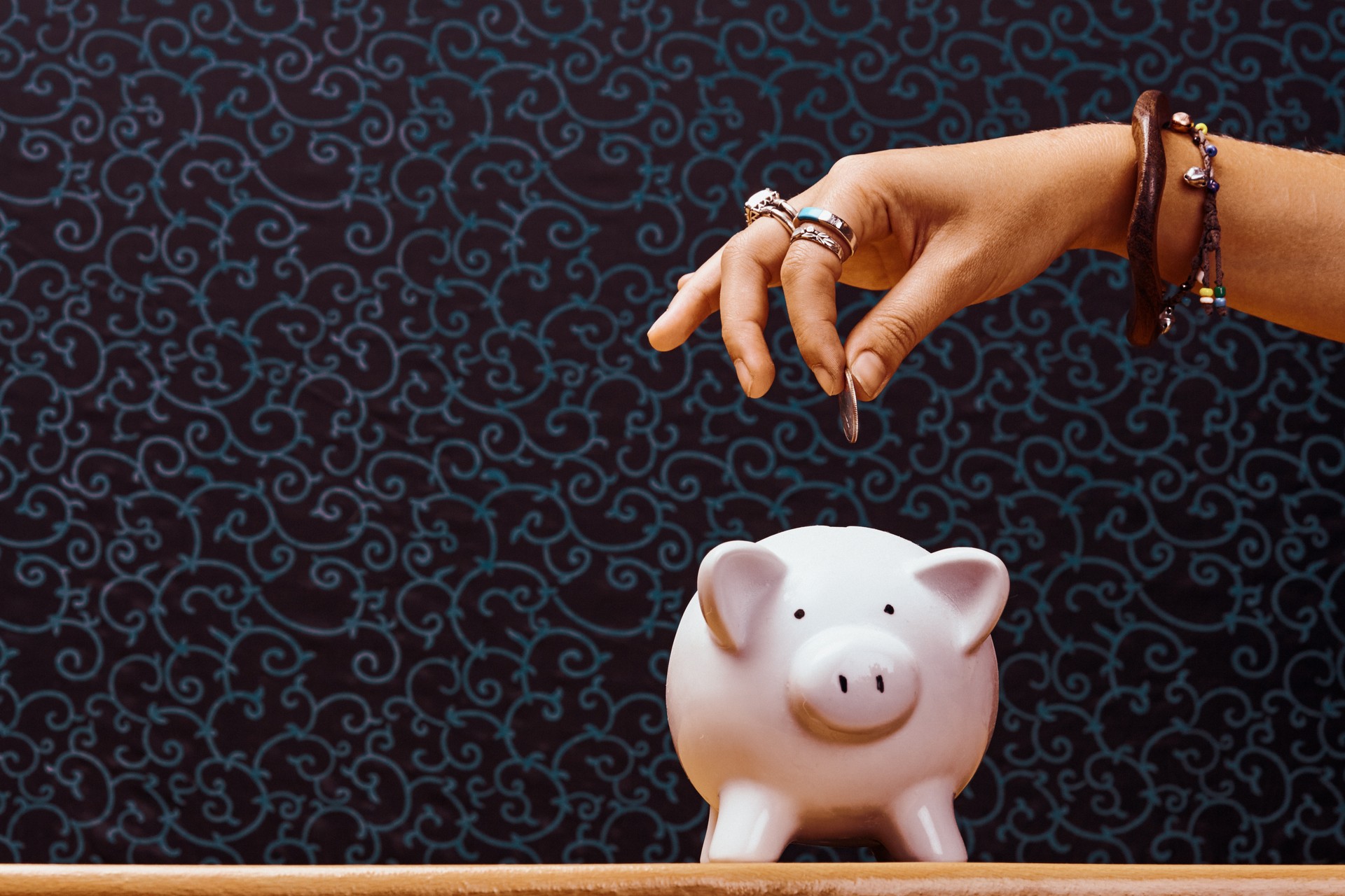 Young woman about to drop a US coin into a porcelain piggy bank